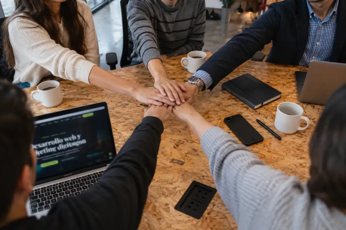 El equipo de Trilven con las manos juntas en una mesa de trabajo